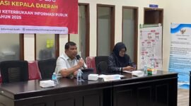 Plt. Sekda Aceh Jaya, Juanda, memaparkan komitmen transparansi pemerintahan di hadapan tim penilai Komisi Informasi Aceh pada kegiatan Monev Keterbukaan Informasi Publik 2025 di Banda Aceh.