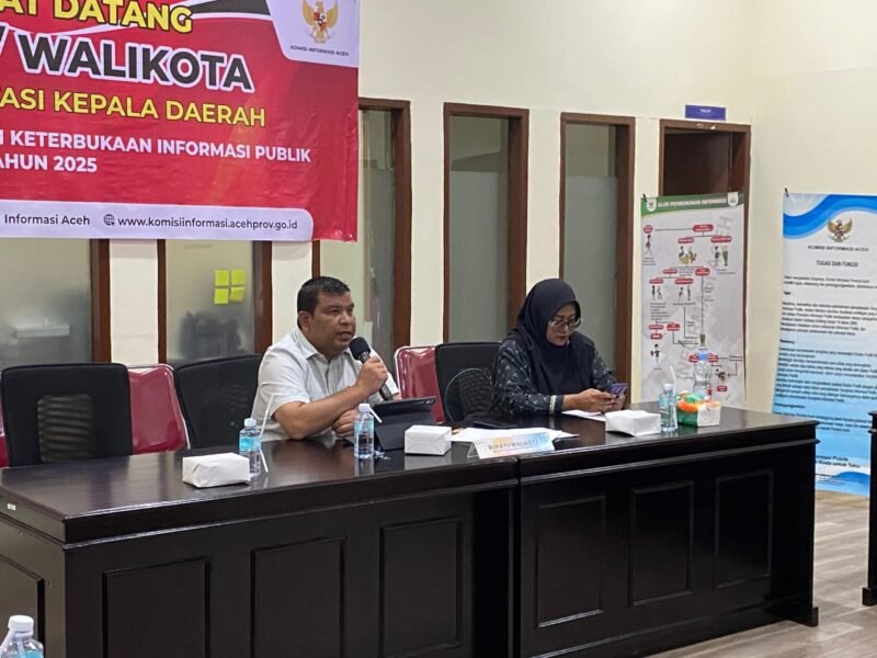 Plt. Sekda Aceh Jaya, Juanda, memaparkan komitmen transparansi pemerintahan di hadapan tim penilai Komisi Informasi Aceh pada kegiatan Monev Keterbukaan Informasi Publik 2025 di Banda Aceh.